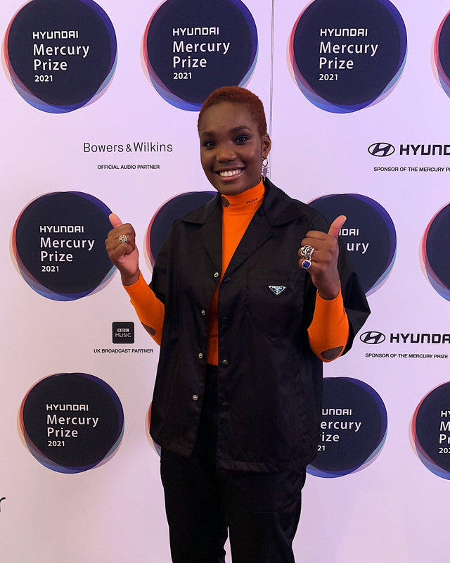 Arlo Parks giving a thumbs-up in front of a Hyundai Mercury Prize backdrop wearing Stephen Einhorn inlaid signet ring with lapis lazuli